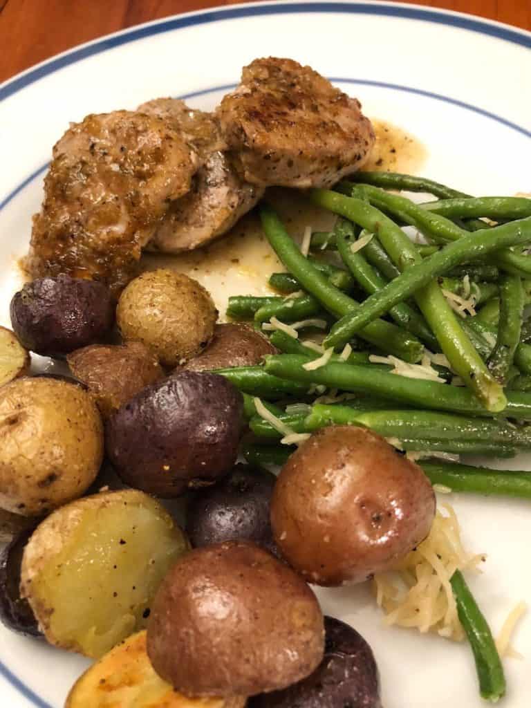 stove top pork tenderloin medallions with chili lime sauce on a plate with green beans and roasted potatoes.
