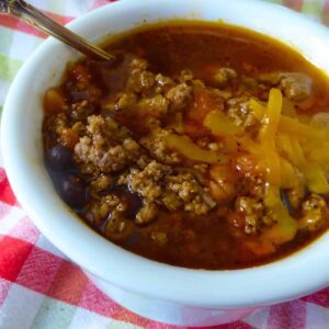 A bowl of chili topped with cheese.