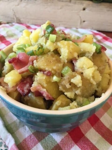 mayo free potato salad with bacon and green onions on a checkered tablecloth