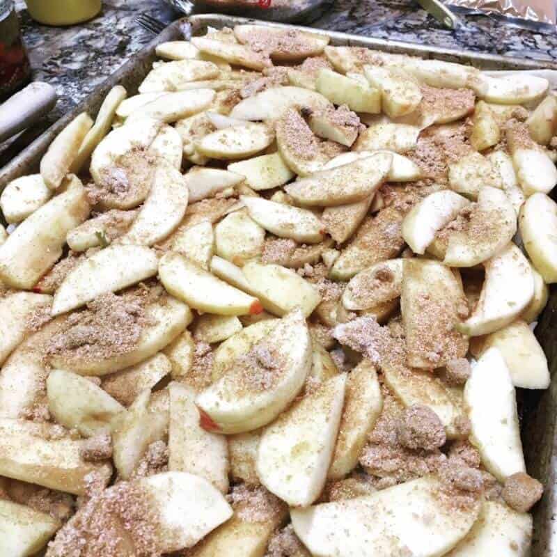 Cinnamon topped apple slices on a sheet pan.