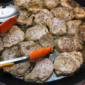 Stove Top Pork Tenderloin Medallions in a pan with chili lime sauce and orange and silver tongs