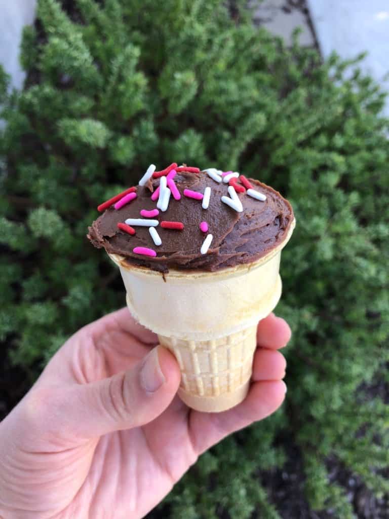 A hand holding an ice cream cone cupcake.