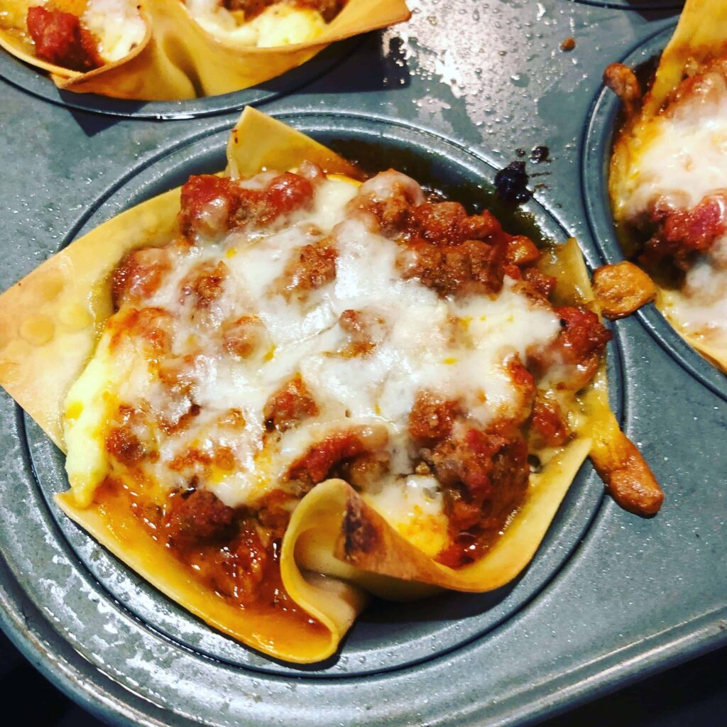 lasagna cup with meat sauce and cheese in a muffin tin.