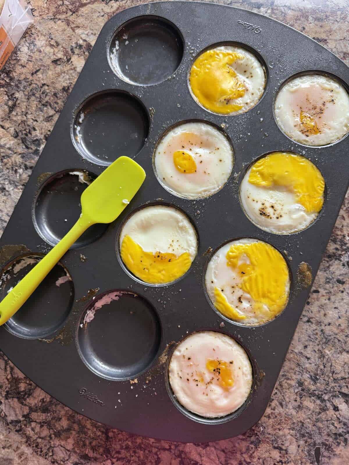 A tray of baked eggs fresh from the oven with set yolks and whites for meal prep.