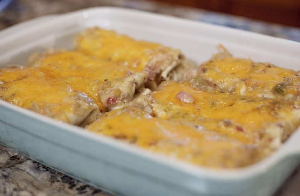 casserole dish with cheese covered green chili pork burritos