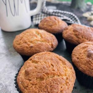 five easy banana bread muffins on a tray with a coffee cup.