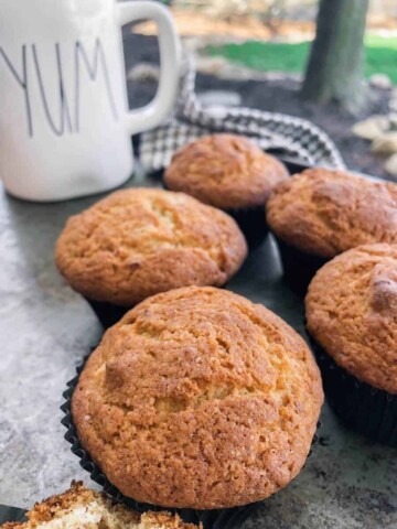 five easy banana bread muffins on a tray with a coffee cup.