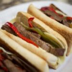 Philly cheese steak sandwiches on rolls with peppers and cheese.