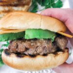Grilled burger with avocado and cheese.