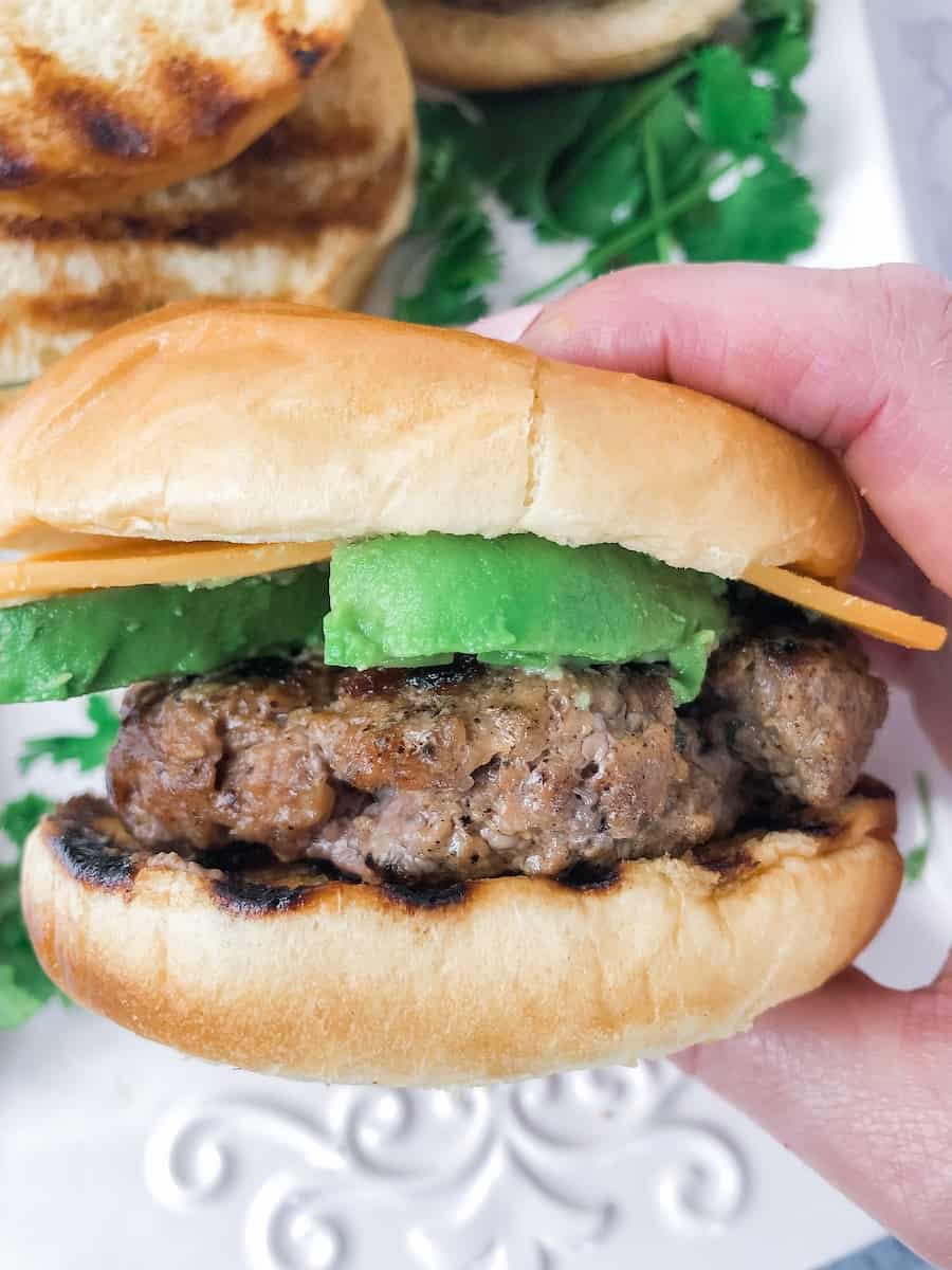 Grilled burger with avocado and cheese.