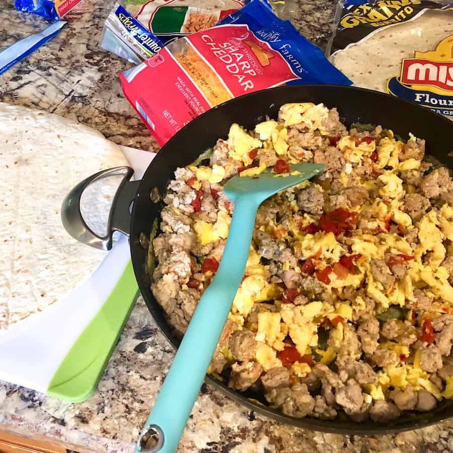 A large skillet filled with scrambled eggs and cooked sausage.