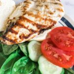 Grilled chicken with tomato slices on the side.