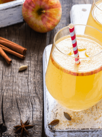 Apple cider punch with an apple slice and a stripe straw.