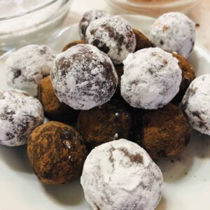 Stack of powdered sugar-coated bourbon balls on a plate.