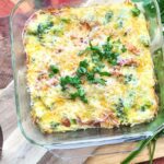 A breakfast casserole topped with cheese and bcon.