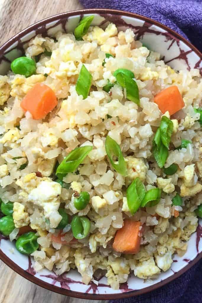 Keto fried rice in a bowl topped with green onions.