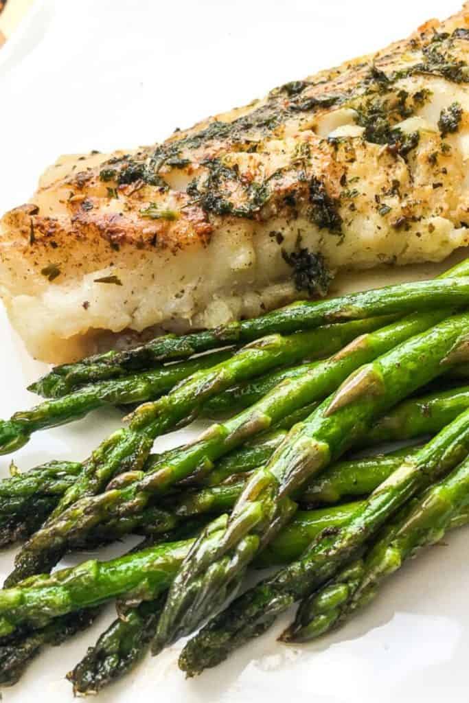Cooked buttered cod and asparagus.