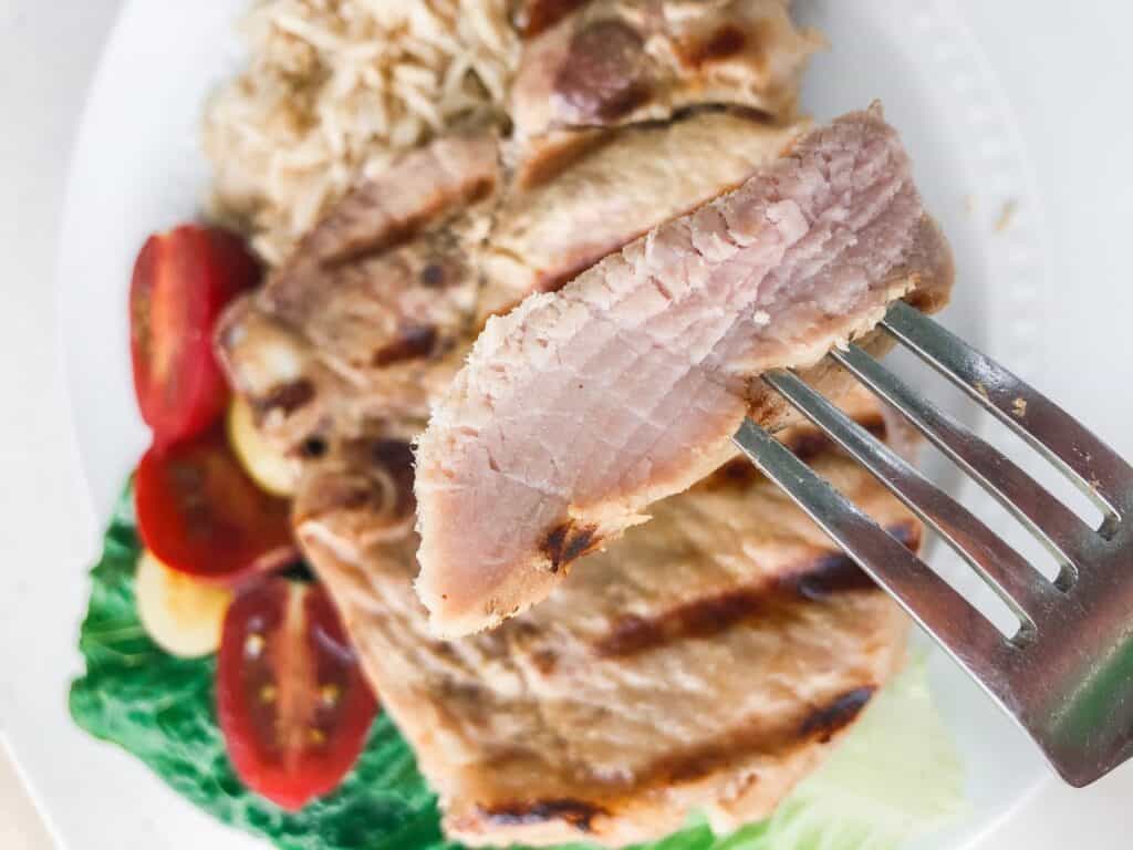 A piece of cooked pork on a fork.