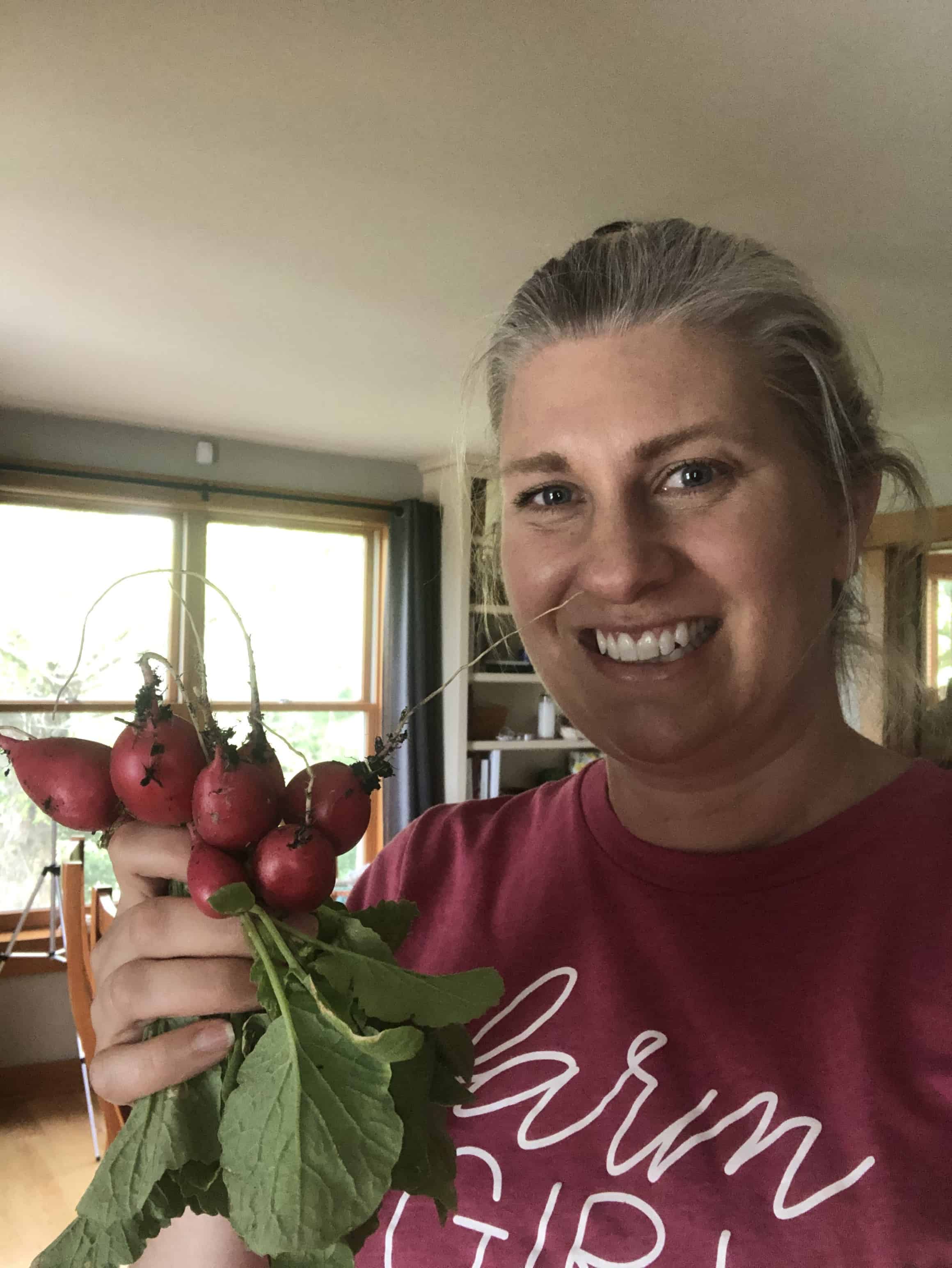 A woman holding a handful of fresh radishes.