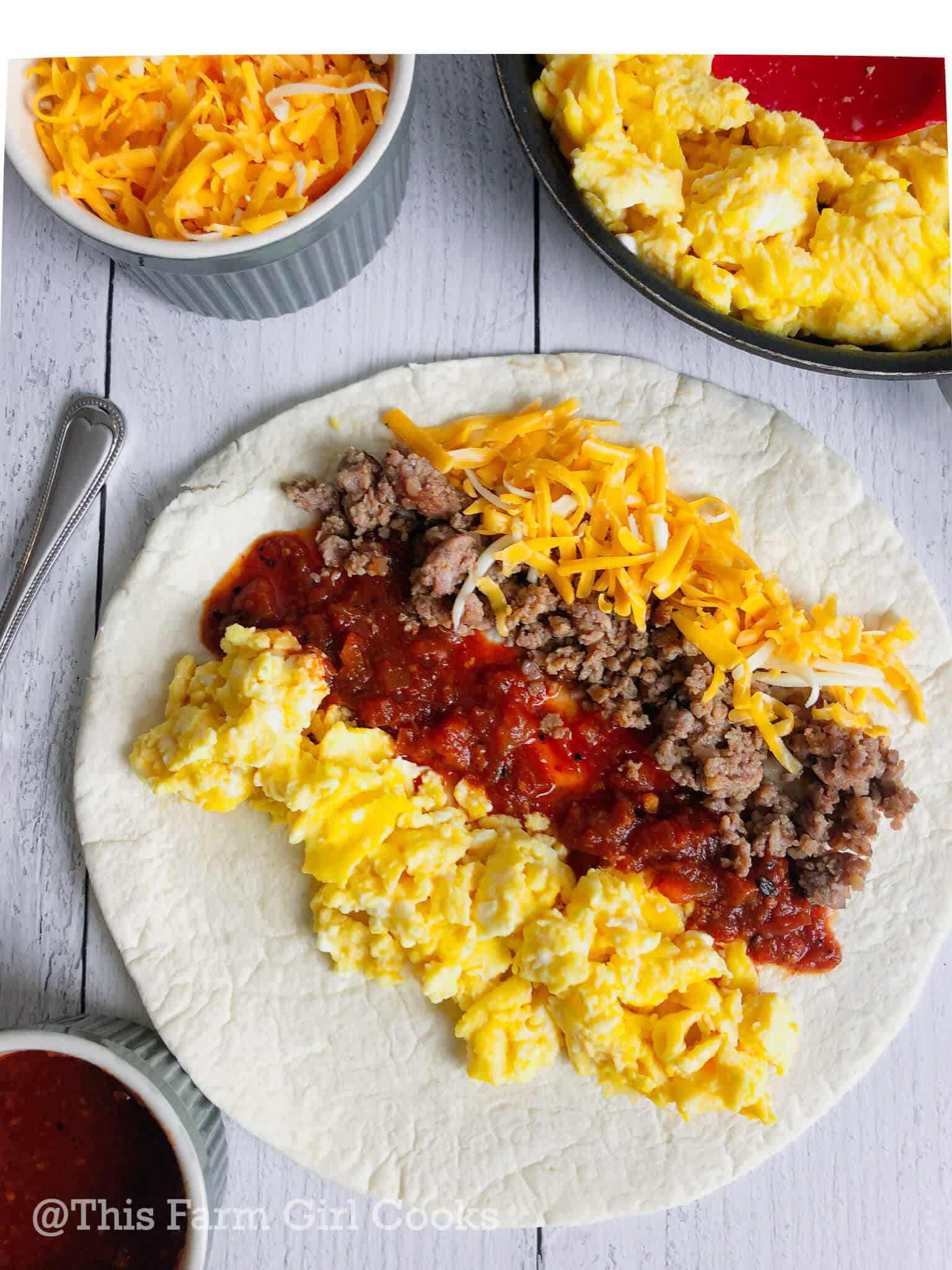 A flour tortilla lined with scrambled eggs, salsa, sausage and cheese.