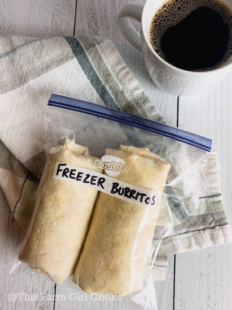 A ziplock bag labeled freezer burritos with two burritos inside of it to be frozen.
