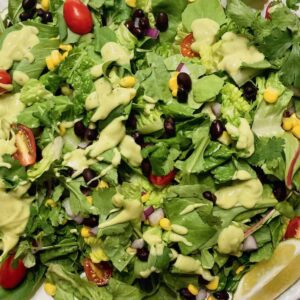 chopped greens with tomato, red onion, and corn topped with creamy avocado dressing