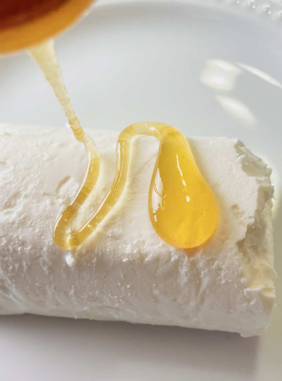 Honey drizzling onto a goat cheese log.