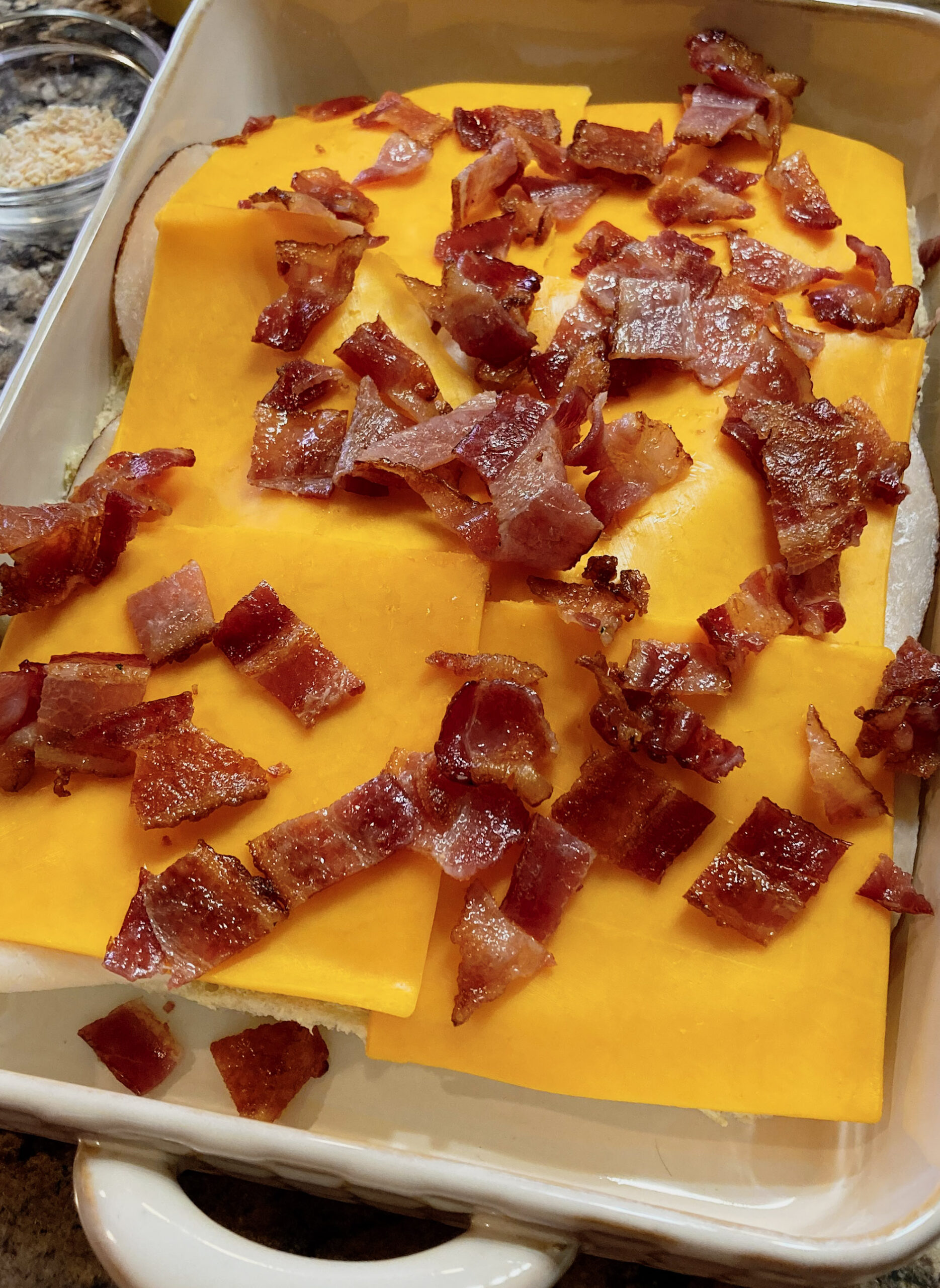 Cheese and bacon topping the chicken and hawaiian rolls, waiting to be topped and baked.