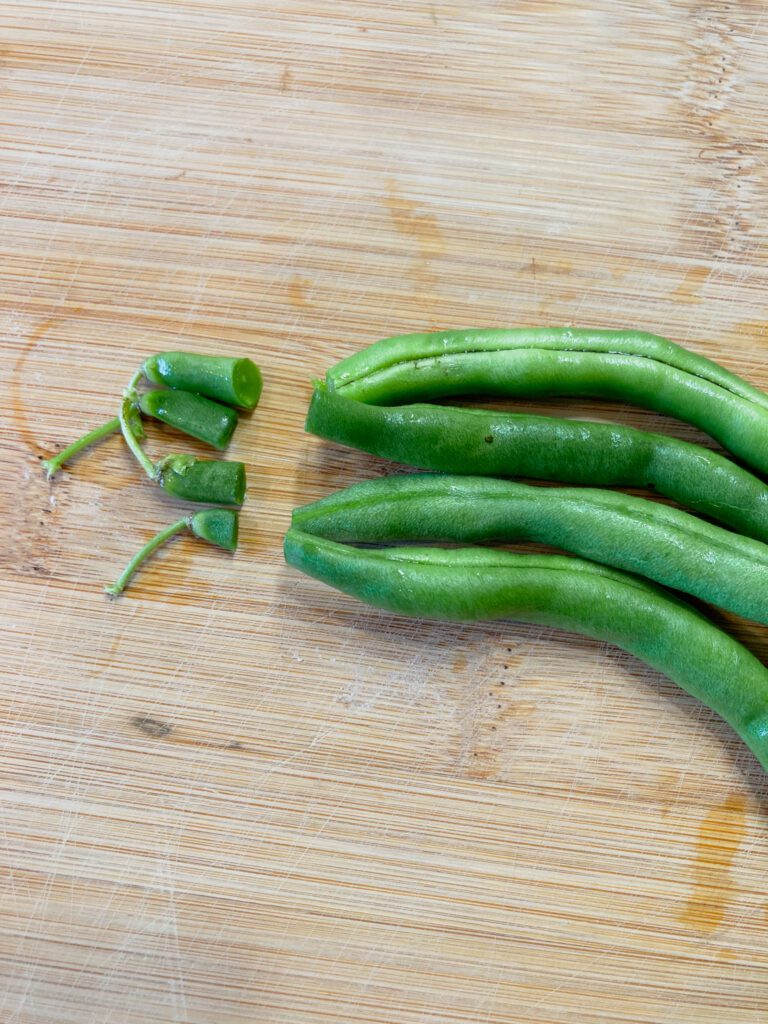 Four green beans with the tips cut off.