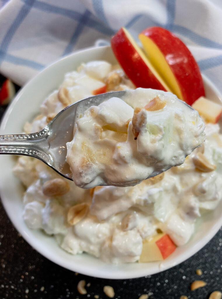 A spoonful of taffy apple salad with sliced apples on the side.