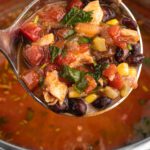 Close-up of hearty crockpot chicken tortilla soup with beans, corn, and shredded chicken.