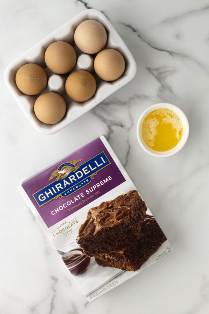 A box of Ghiradelli brownie mix with eggs and butter.