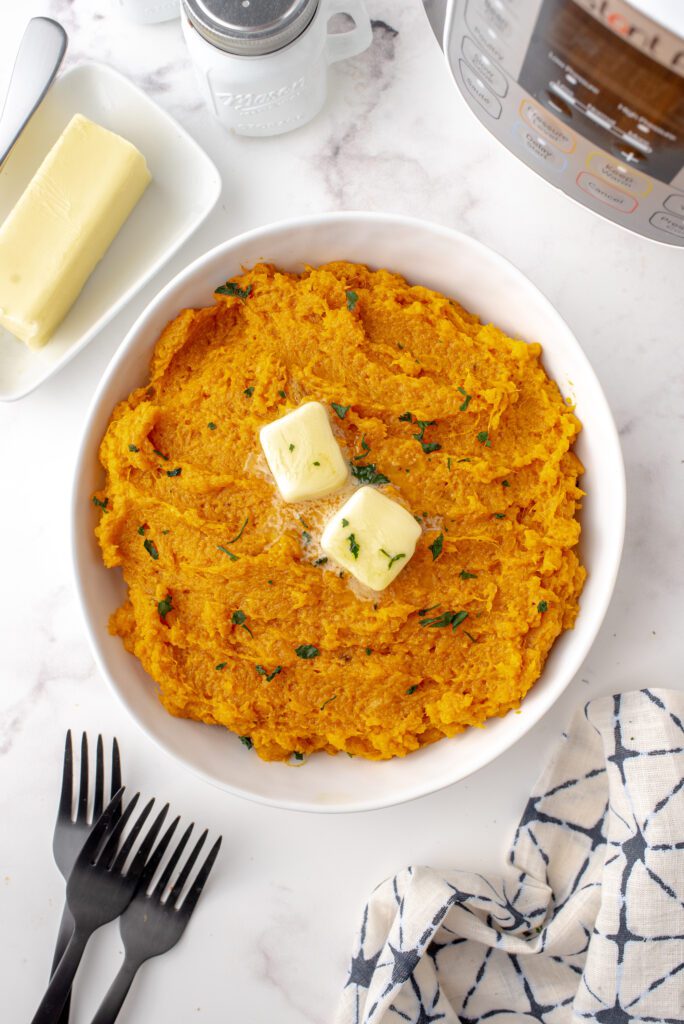 Mashed sweet potatoes topped with a pat of butter.