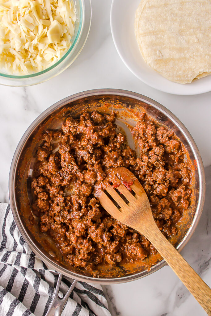taco meat in a skillet with cheese and tortillas