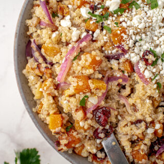 Butternut Squash quinoa salad in a bowl with crumbled goat cheese on top.