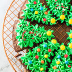Fudgy Christmas brownies decorated like Christmas trees with green frosting and sprinkles.