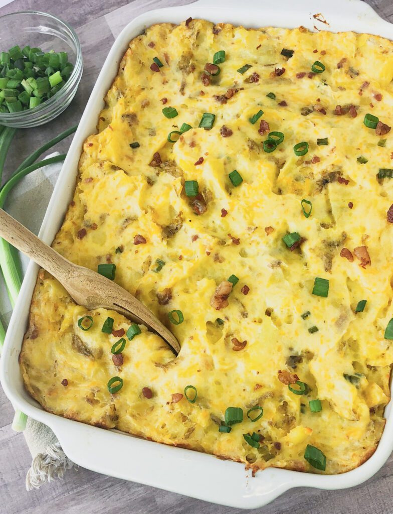 Twice baked mashed potatoes in a casserole dish topped with bacon and green onion.