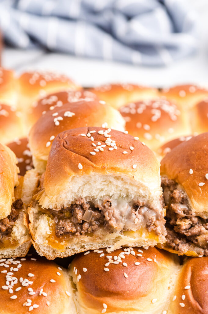 Cheeseburger sliders on hawaiian rolls topped with sesame seeds.