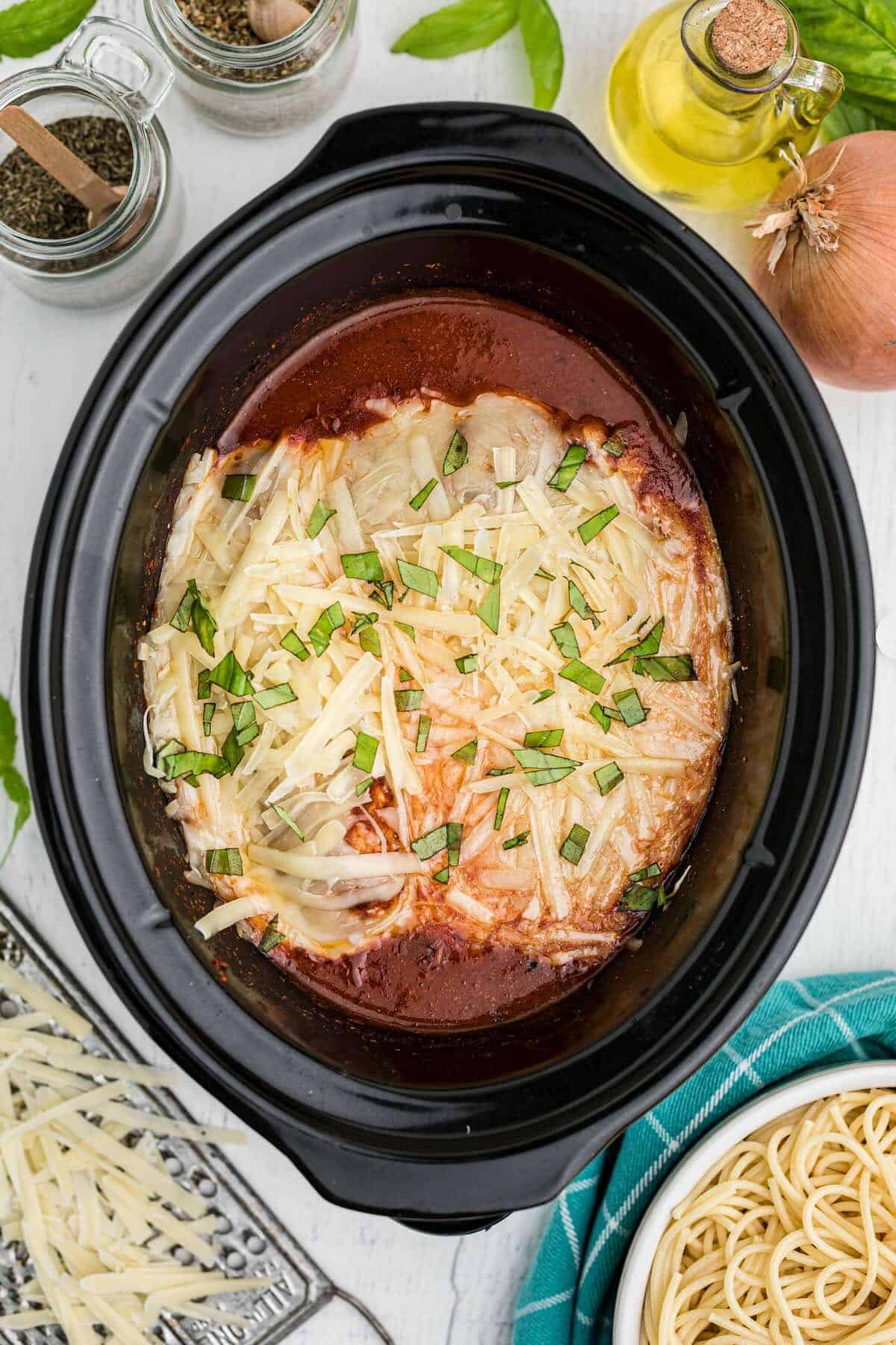 Crockpot Chicken Parmesan topped with melted mozzarella and fresh basil, ready to serve.