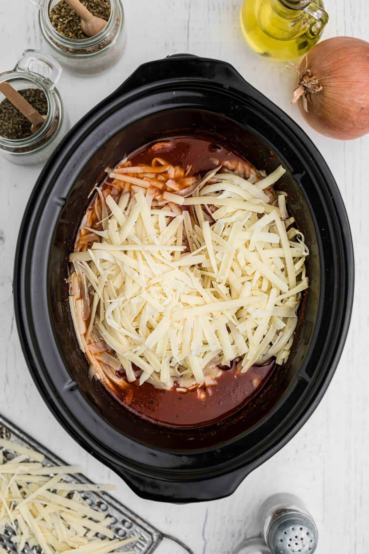 Mozzarella and parmesan melting over Crockpot Chicken Parmesan in slow cooker.
