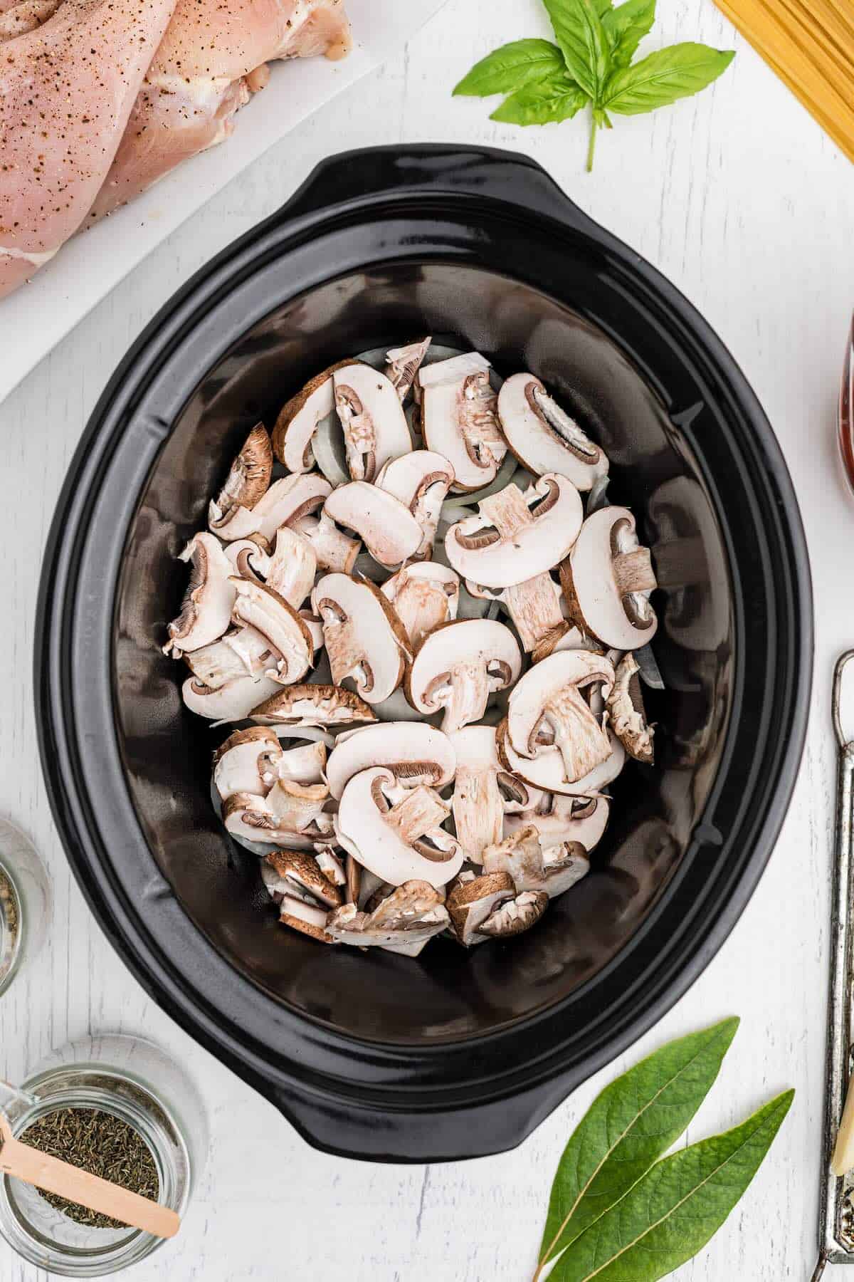 Mushrooms and onions in an oval shaped crockpot.