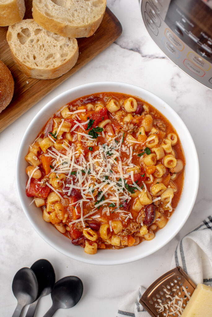 A bowl full of pasta fagioli soup topped with grated Parmesan cheese.