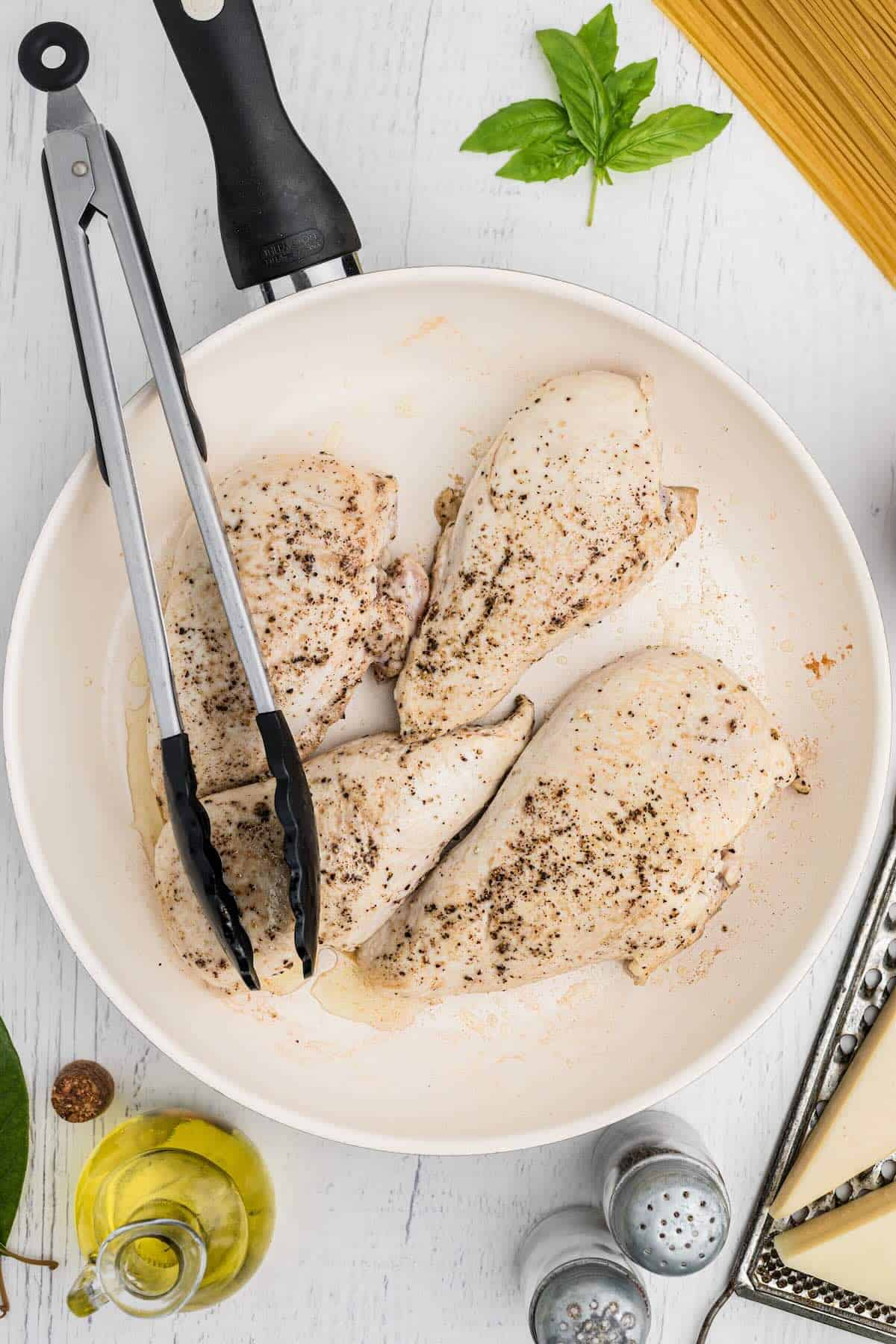 Chicken breasts searing in a skillet before going into a crock pot.