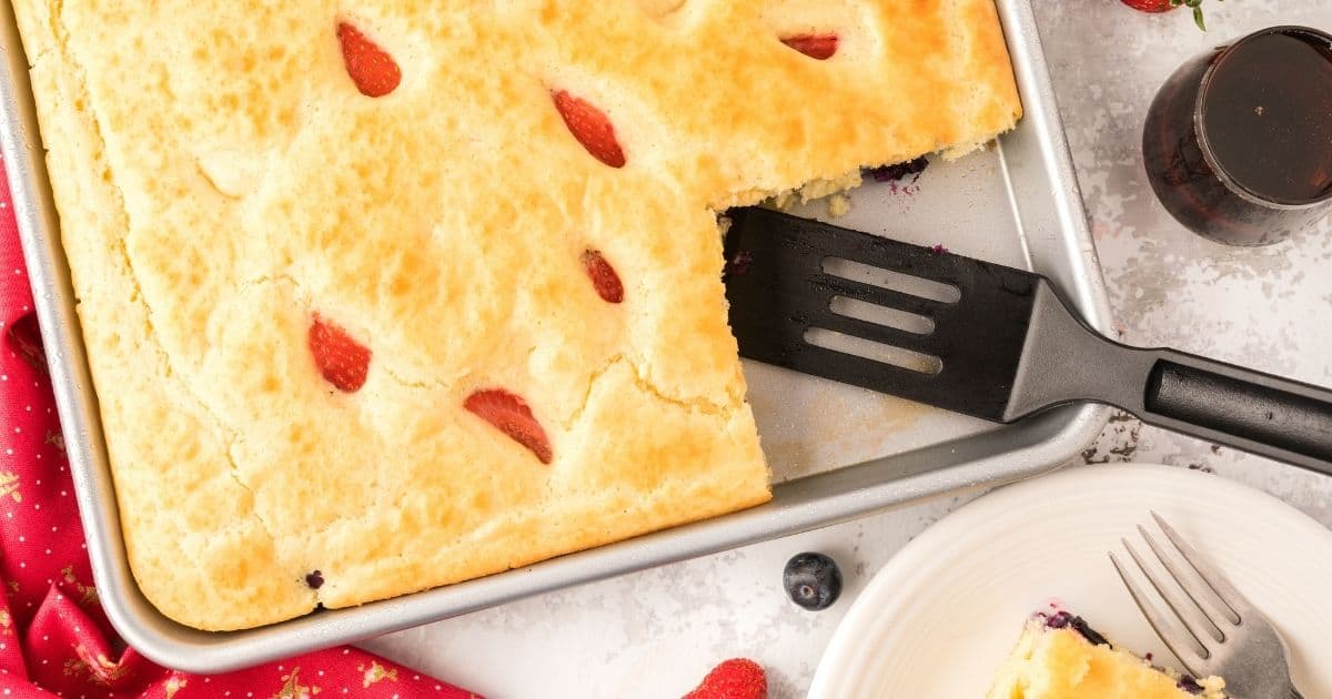 A tray of pancakes cooked in a sheet pan with fruit baked in.