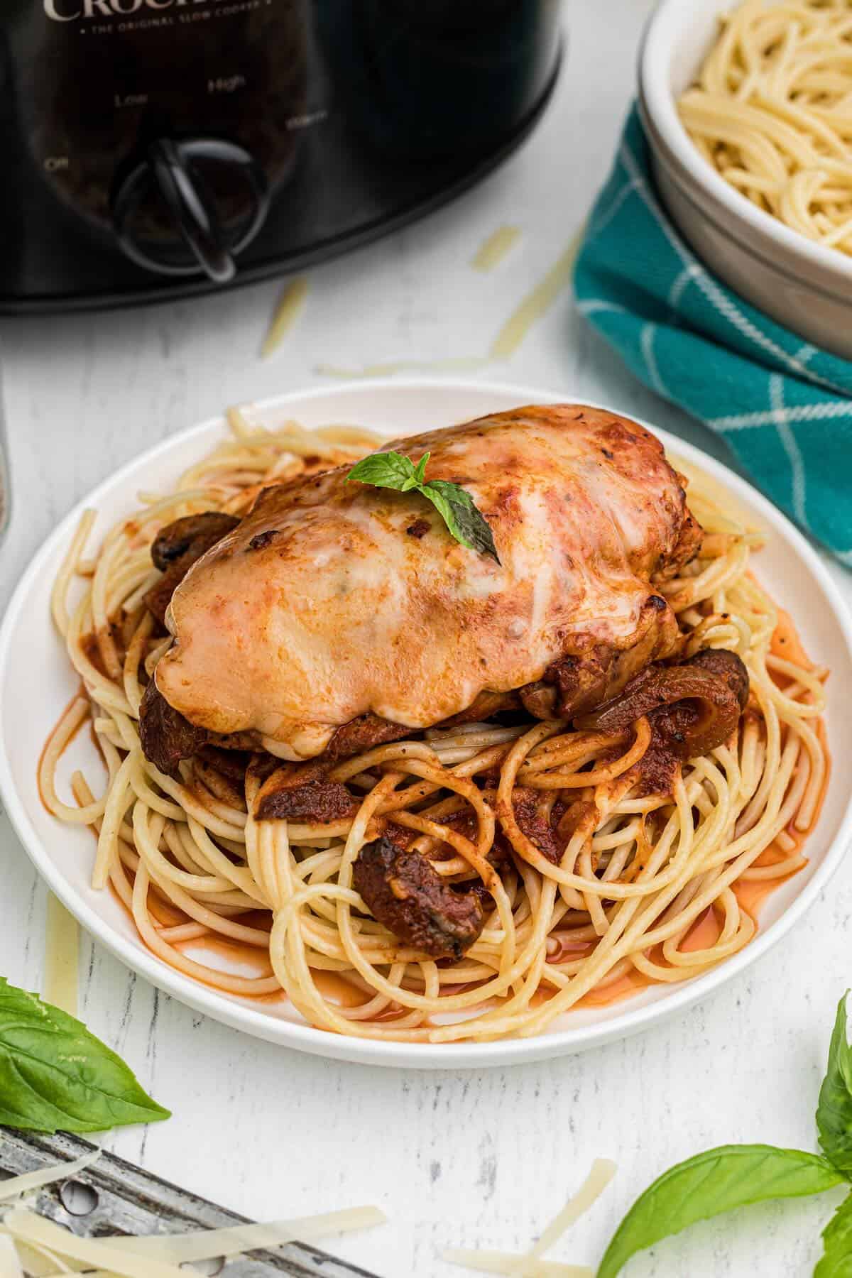 A plate of chicken parmesan with cheese served over pasta.
