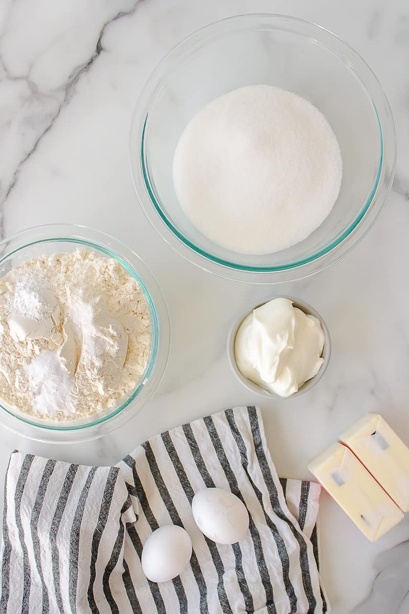 Ingredients to make sour cream cookies with eggs, butter, sugar, flour.