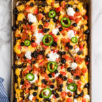 Totchos topped with sour cream, olives, jalapeno slices and cheese.