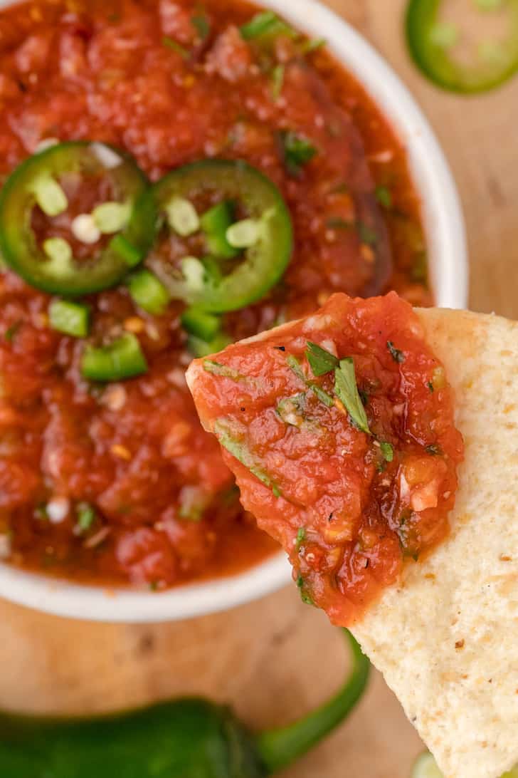 A scoop of restaurant style salsa on a tortilla chip.
