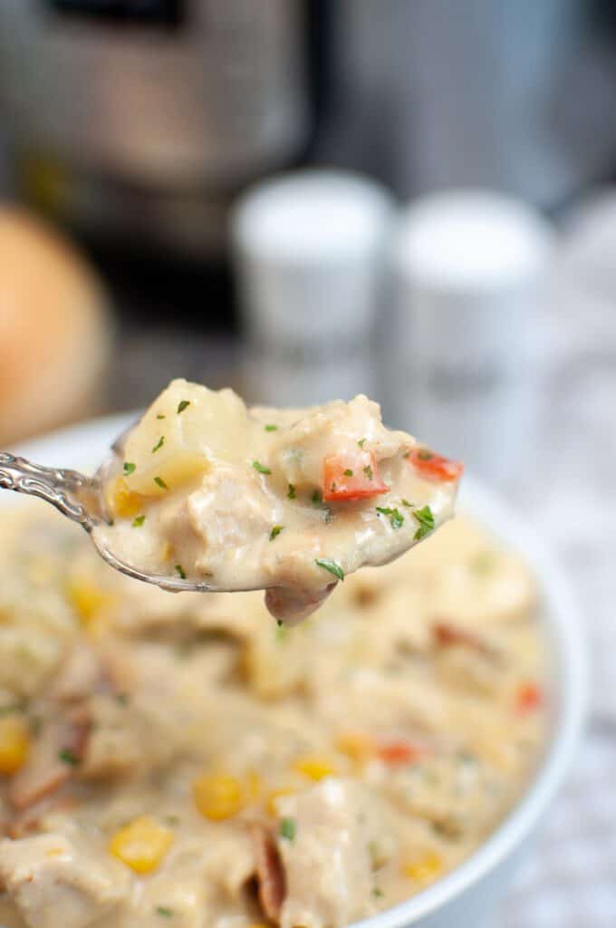 A spoonful of chicken corn chowder with meat and potatoes.