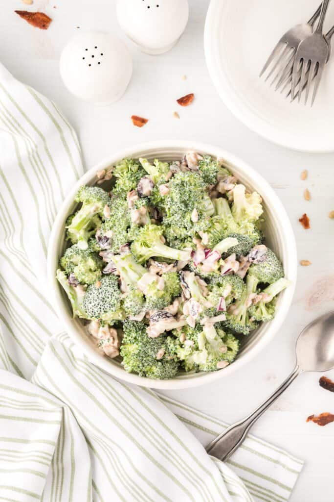 A bowl of broccoli salad topped with craisins and sunflower seeds.
